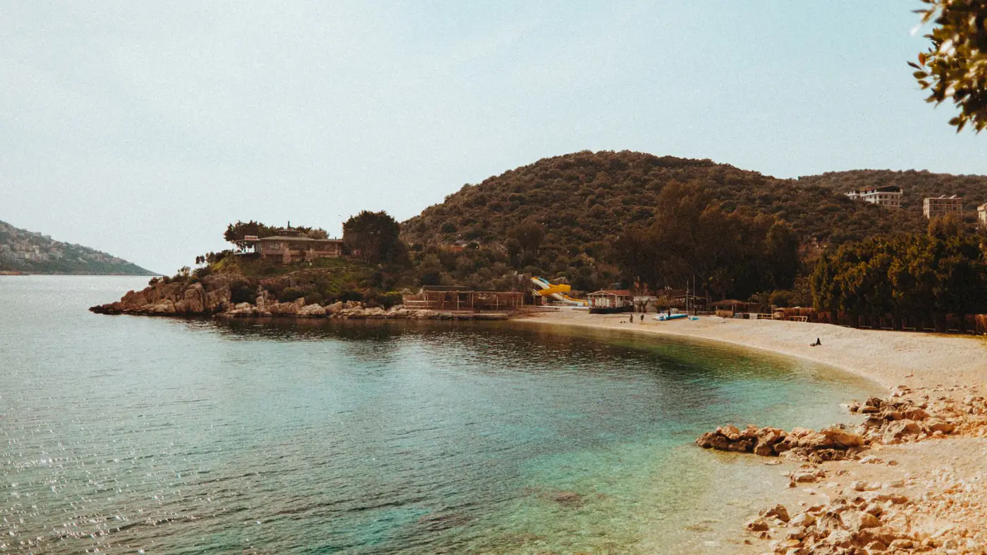 Relaxing beach scene with clear waters and lush greenery under a sunny sky, perfect for travel inspiration.