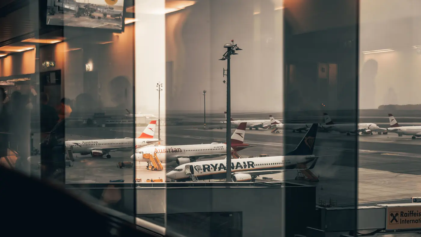 Airplanes at a bustling airport with reflections of interiors in the window panes.