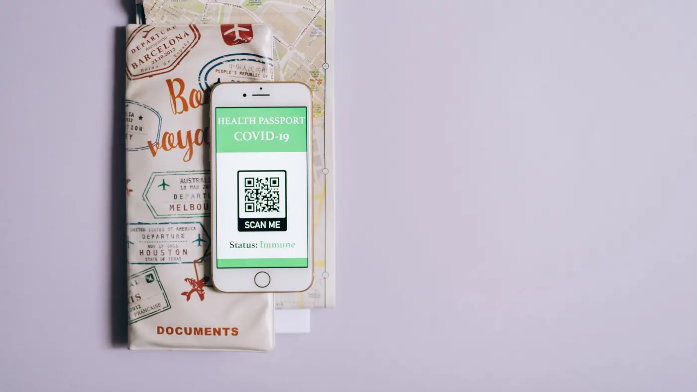Smartphone displaying a COVID-19 health passport with travel documents on a purple background.