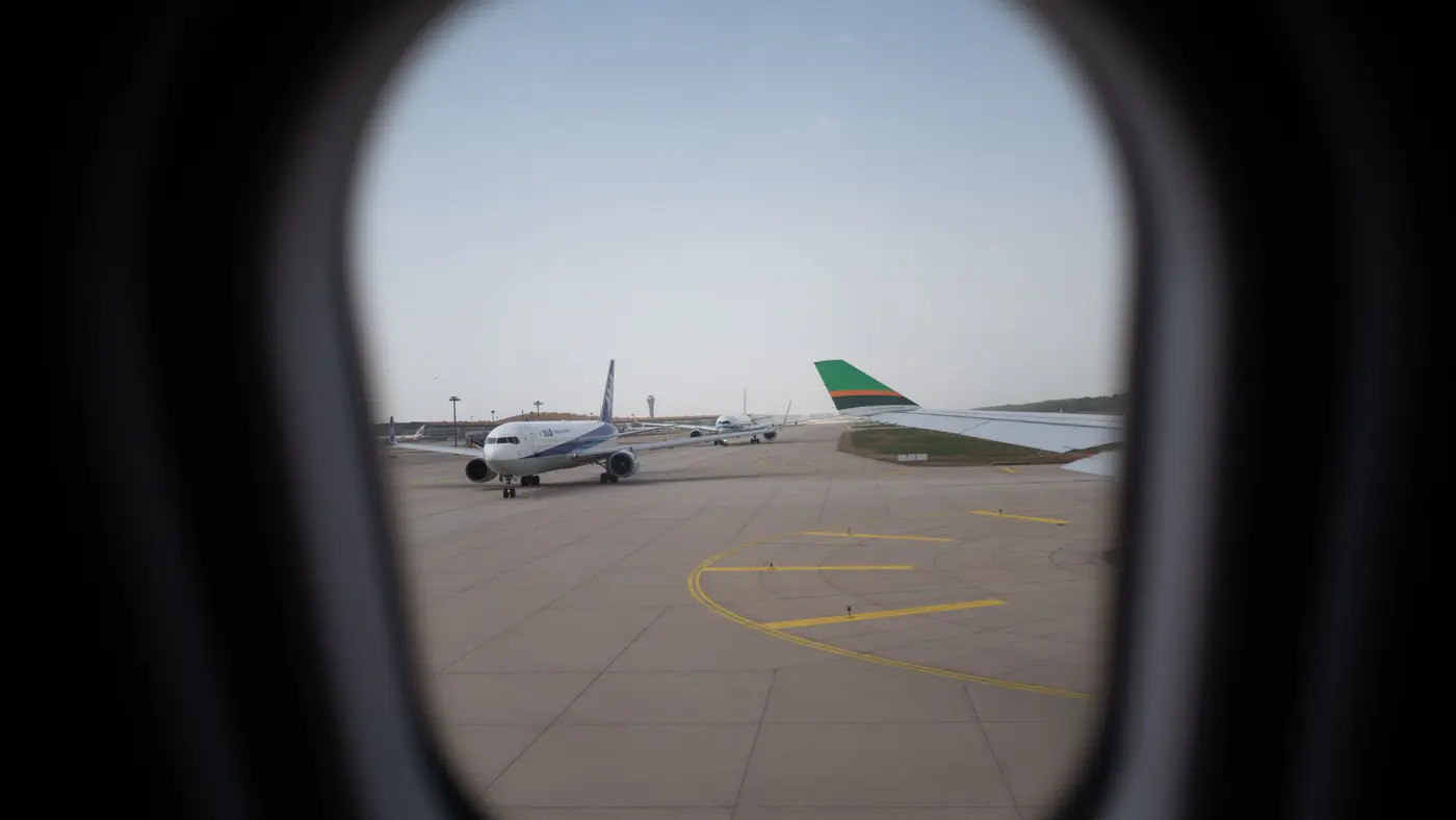 Airplane seen through a window, parked on the airport runway, capturing a travel moment.