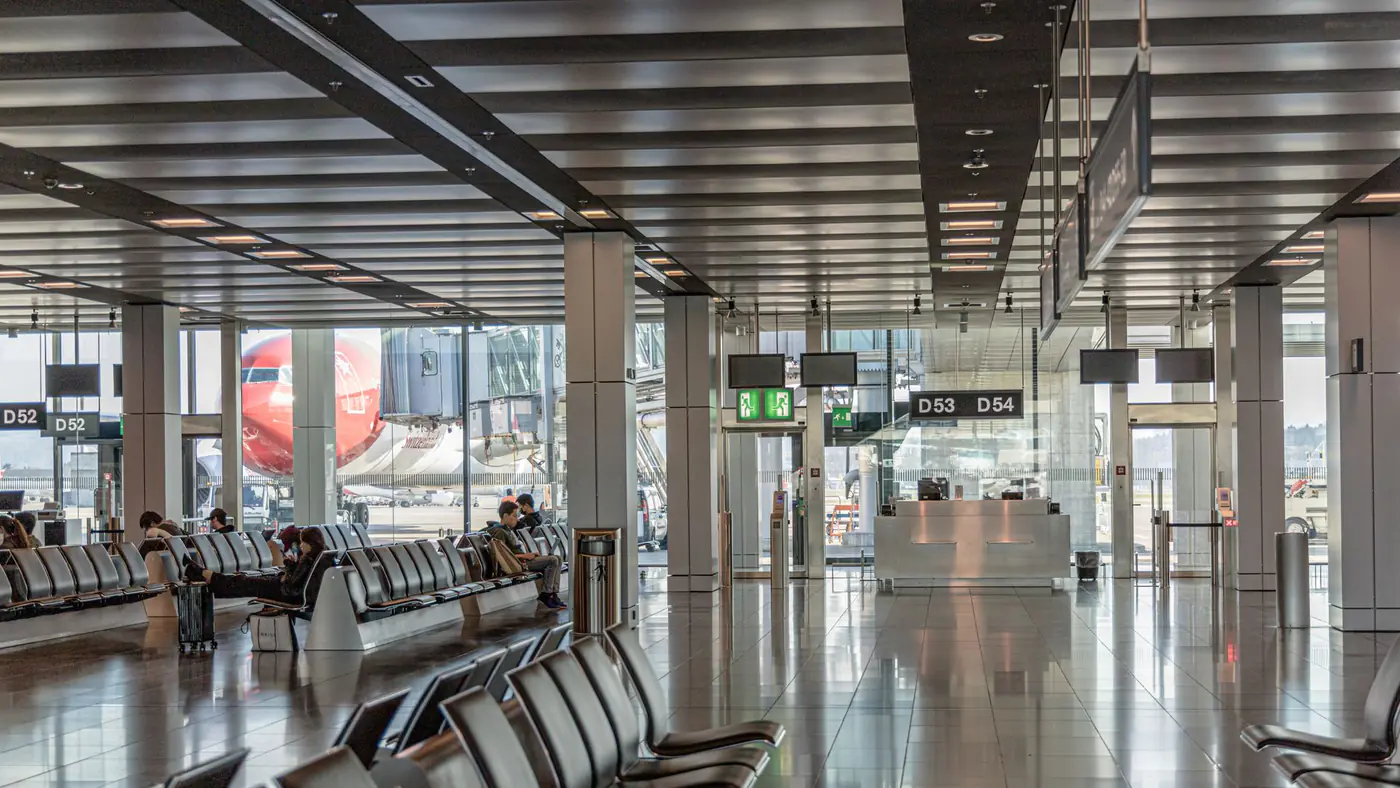 Spacious airport terminal with empty seating and a view of an airplane through large glass windows.