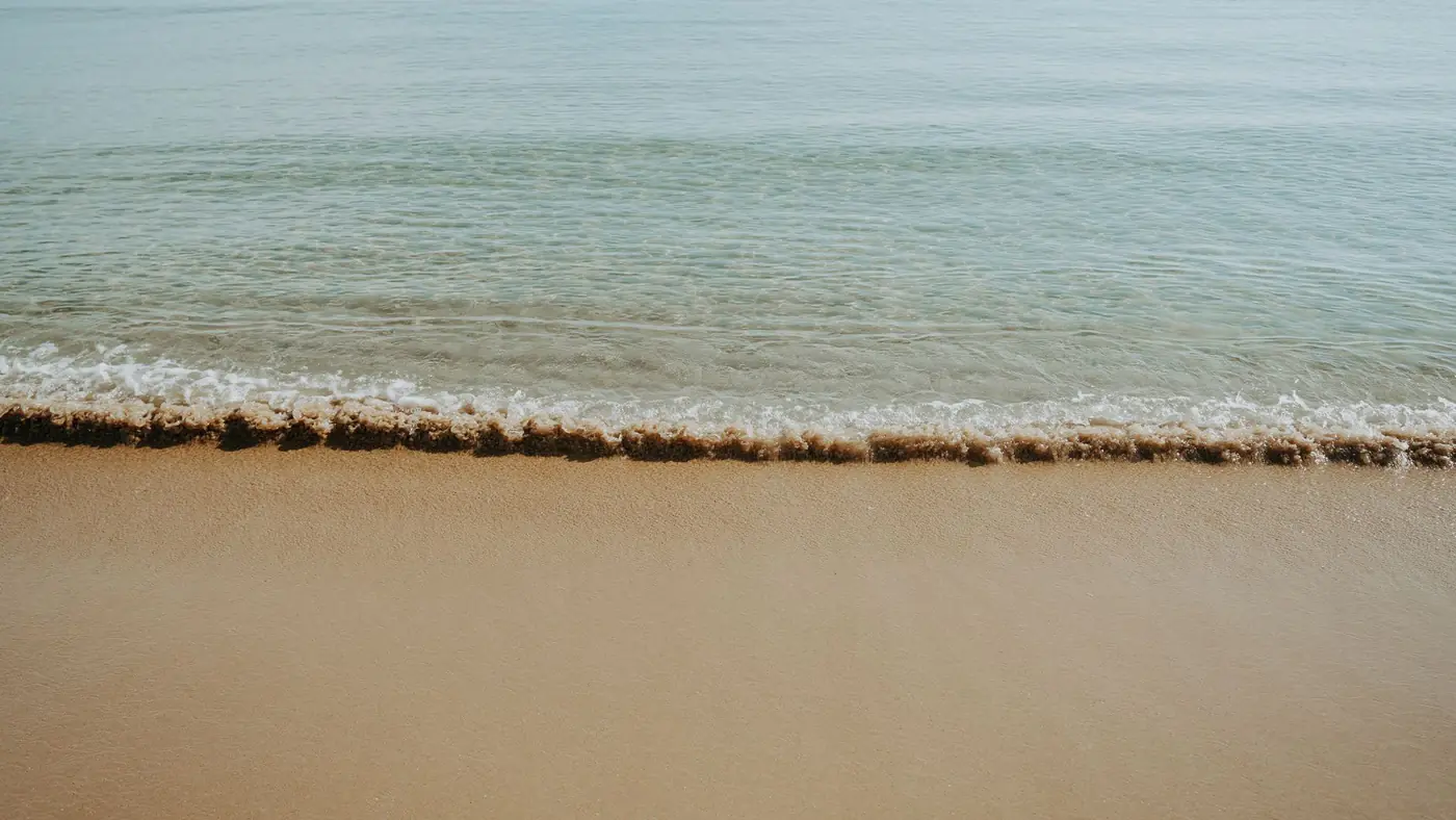 Calm and serene beach with gentle waves lapping on the sandy shore. Perfect for relaxation.