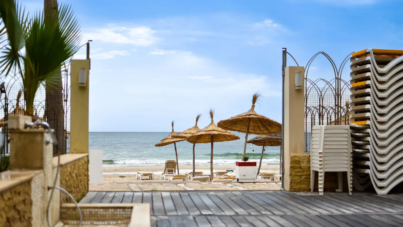 Tranquil beach scene with straw umbrellas and lounge chairs in Tunis, Tunisia.
