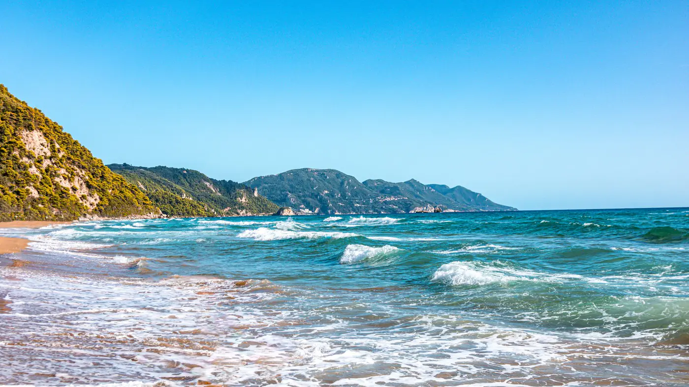 Explore the serene beach in Greece with blue waves and sunny summer vibes. Perfect for travel inspiration.