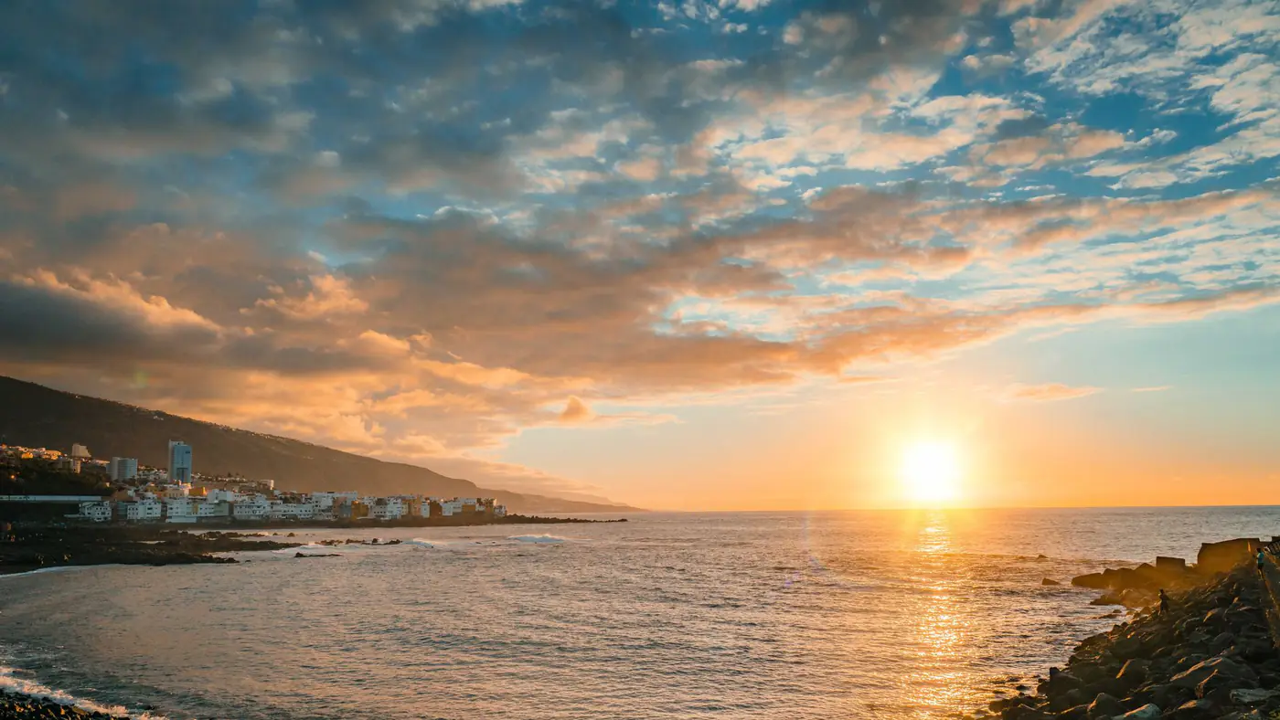 Stunning sunset view over the ocean in Puerto de la Cruz, Spain, showcasing vibrant skies and serene waters.