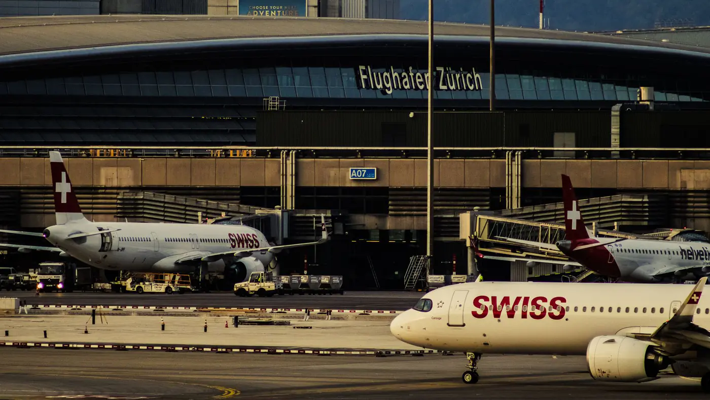 Swiss Airlines planes parked at Zurich Airport with clear view of terminal building.